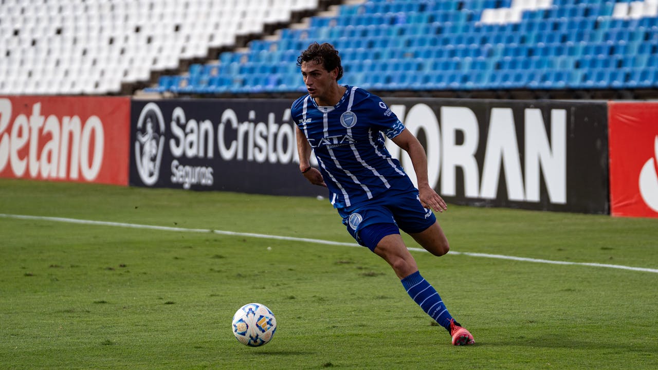 Action shot of a soccer player in motion on a football field with advertising boards.
