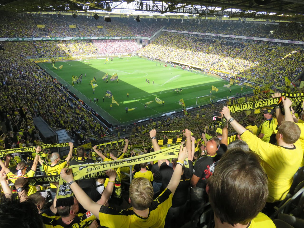 Excited Borussia Dortmund fans cheering during an intense soccer match at the stadium.